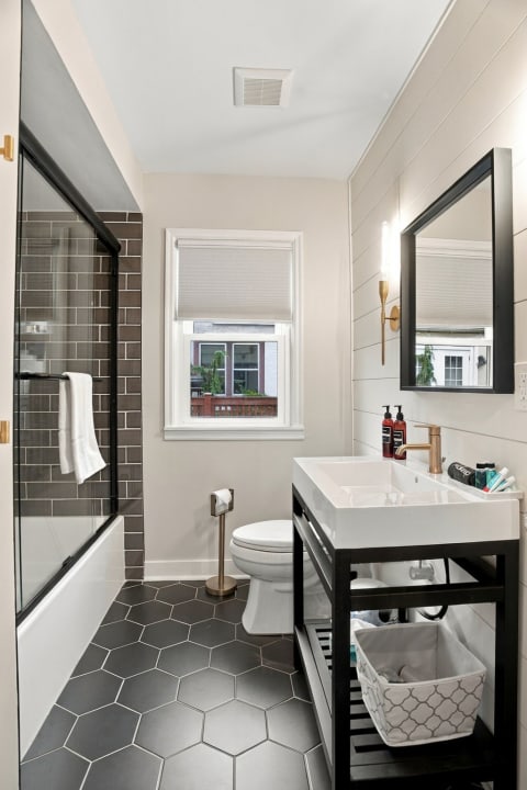 Modern bathroom with shiplap walls, hexagon tile flooring, and walk-in shower.