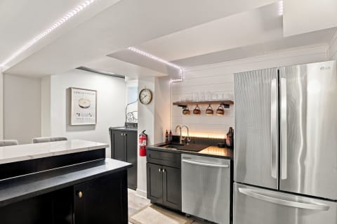 Modern kitchen with black cabinetry and stainless steel appliances, featuring an island and open shelving.