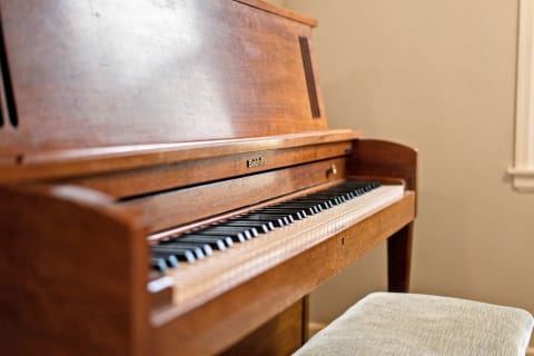 A close-up view of a Baldwin piano showcasing its polished wooden surface and black and white keys, alongside a soft stool.