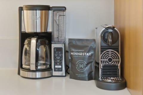 An organized coffee station with a Ninja coffee maker, an espresso machine, and a packet of MINNESTAY coffee.