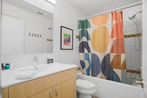 Modern bathroom with geometric shower curtain and sleek wood vanity.
