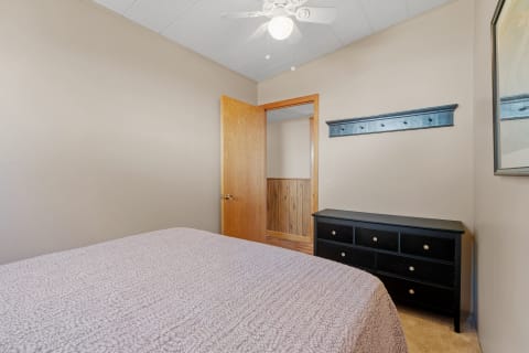 A cozy bedroom featuring a bed with a purple comforter, a black dresser, and an open door leading to another space.