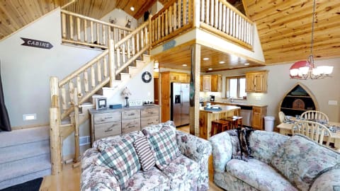 Interior view of a rustic cabin with wooden accents and floral furniture.