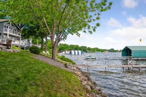 A scenic view of a lakeside home and dock area, surrounded by trees and water.