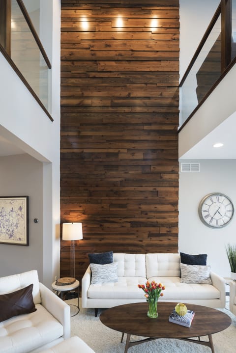 Modern living room with a wooden accent wall, white sofas, and decorative elements.