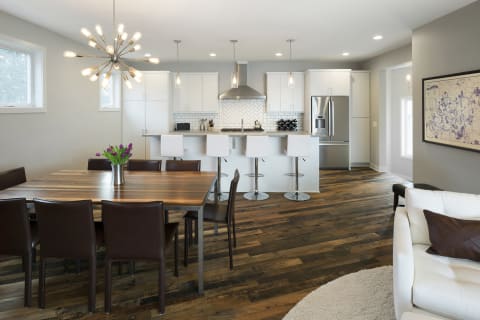 Open-concept kitchen and dining area with white cabinets, dark wood flooring, and a starburst chandelier.