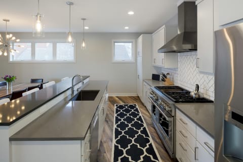 Contemporary kitchen with a dark gray island, stainless steel appliances, and a geometric rug.