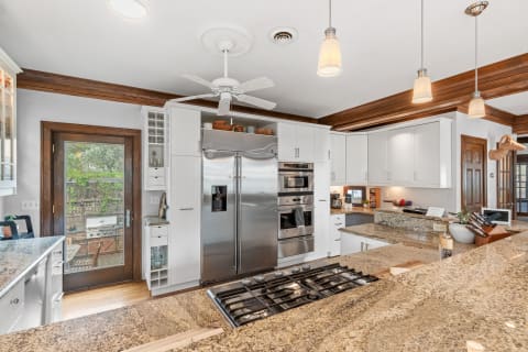 Modern kitchen with white cabinets, granite countertops, and stainless steel appliances.