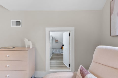 Cozy room interior with wooden dresser and an open door leading to another space.