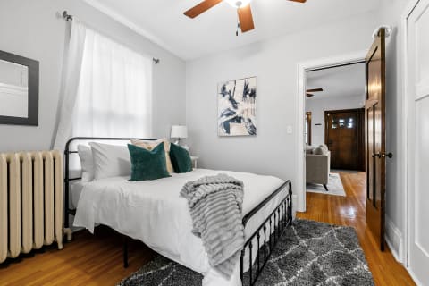 A stylish bedroom with a modern bed, teal pillows, and natural light.