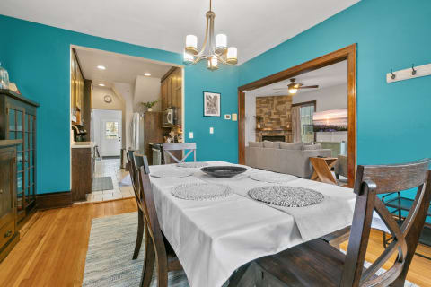 Dining area with teal walls, wooden furniture, a set table, and views into the kitchen and living room.