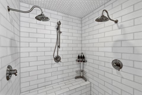 A spacious shower area with white subway tiles and multiple showerheads.