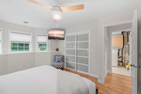 Interior view of a bright bedroom featuring a bed, window, television, and closet.
