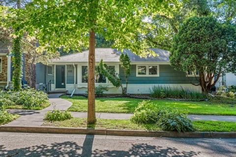 Single-story house with green siding and a well-maintained lawn.