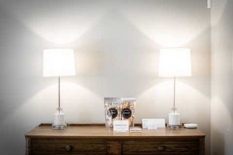 A wooden dresser adorned with two lamps, a bag of popcorn, and guest cards, creating a warm atmosphere.