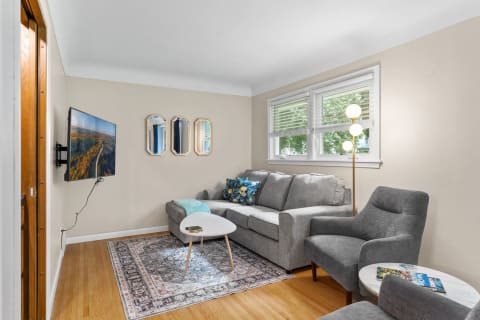 A comfortable living room with a grey sofa, patterned rug, and stylish decor.