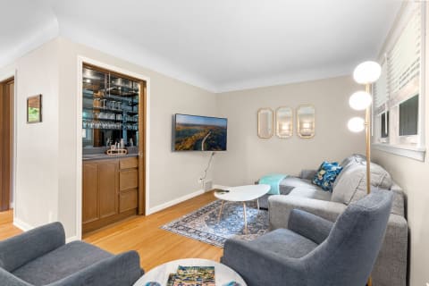 A cozy living room with a gray sectional sofa, a minimalist coffee table, and a bar area with glassware.