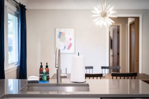 Contemporary kitchen with sleek countertop, amber soap bottles, and a starburst chandelier.