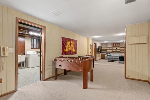 Interior of a basement featuring a foosball table, laundry room door, and a cozy sitting area.