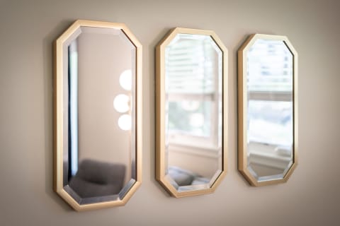 Three octagon-shaped mirrors with gold frames hanging on a light wall, with reflections and a cozy background.