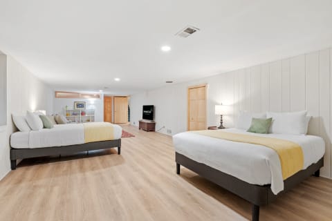 A well-lit room featuring two large beds and a wooden floor.
