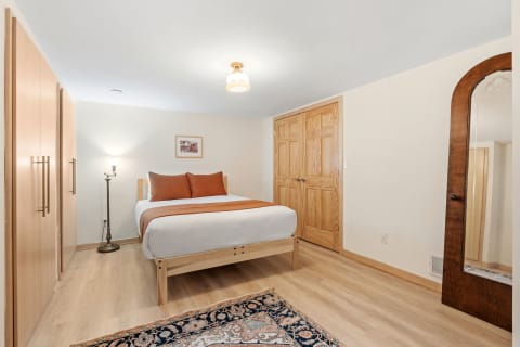 Cozy bedroom with a bed, floor lamp, wardrobe, and mirror.