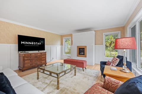 Living room with a flat-screen TV, wooden furniture, and colorful chairs.