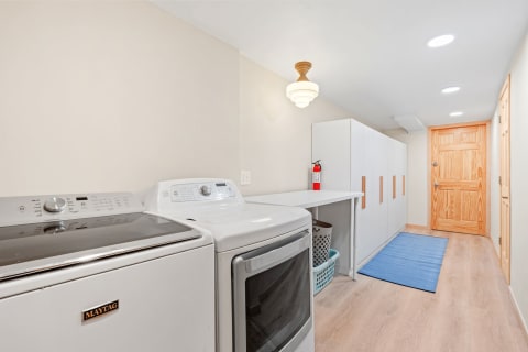A clean laundry room with a Maytag washer and dryer, counter space, and white cabinetry.
