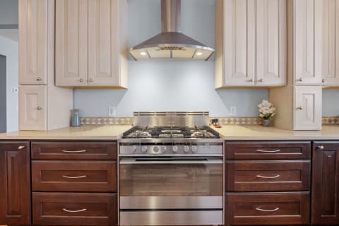 A contemporary kitchen with a gas stove and dual-tone cabinetry.