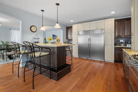 Interior view of a modern kitchen featuring an island, bar stools, and stainless steel appliances.