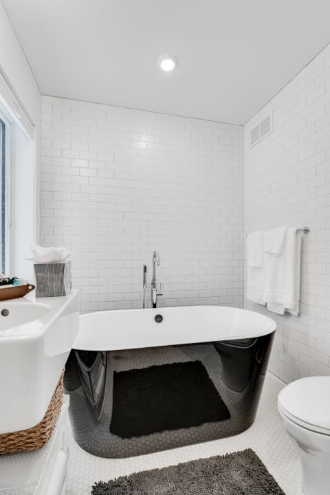 Sleek modern bathroom with a freestanding bathtub and white subway tile walls.