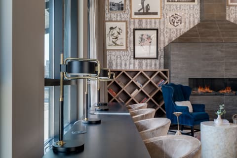 A modern lounge area with lamps, bookshelves, artwork, and a fireplace.