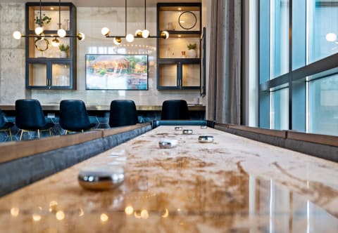 Modern conference room with shuffleboard table, plush chairs, and bright city views.