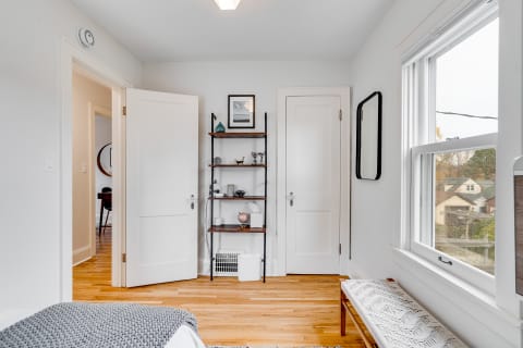 Interior view of a stylish room with an open door, decorative shelf, and wooden floor.