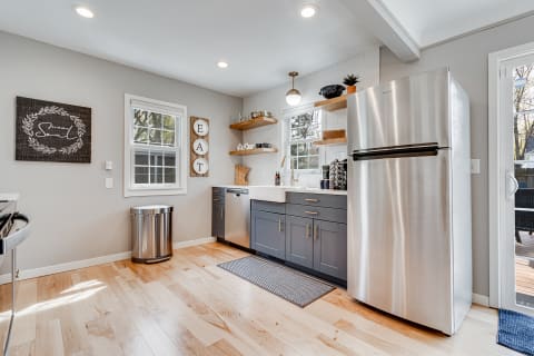 A contemporary kitchen featuring gray cabinets, a stainless steel refrigerator, and rustic decor.