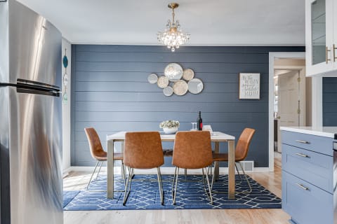 A contemporary dining space featuring a white table, brown leather chairs, and blue wall decor.