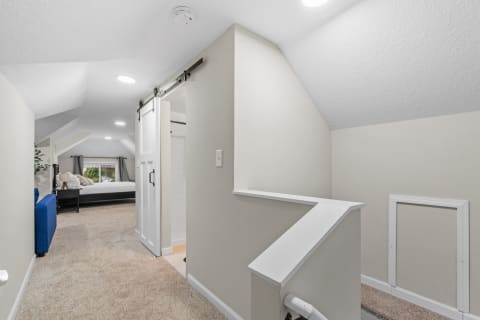 Interior view of an upstairs hallway with a sliding barn door and a glimpse of a bedroom.