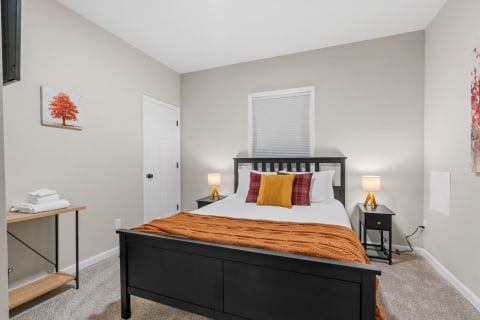 Cozy bedroom featuring a black bed, colorful pillows, and warm lighting.