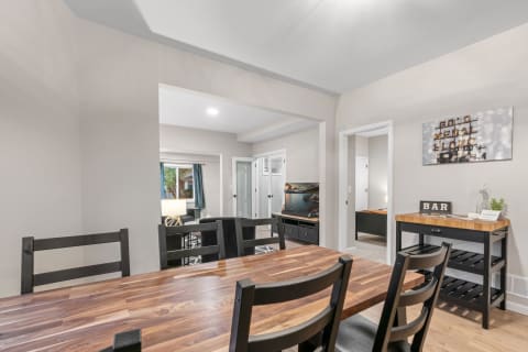 Modern dining area with wooden table, black chairs, and connected living space.