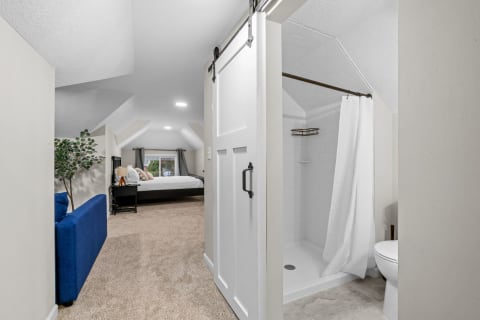 Cozy loft bedroom with a sloped ceiling and adjoining bathroom.