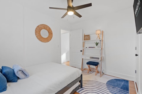 Minimalist bedroom with a bed, shelving unit, and decor in soft colors.