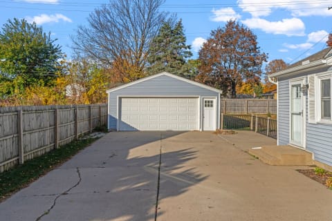 Driveway with a light blue garage and autumn trees