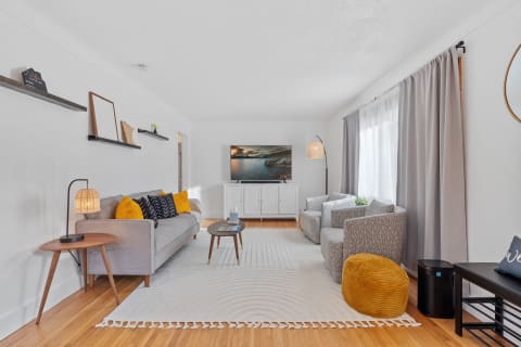 Modern living room with gray furniture, wooden accents, and decorative elements.