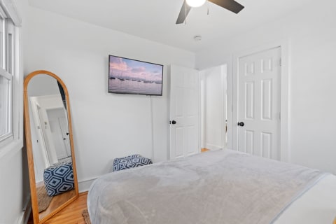 Cozy bedroom with modern decor, wall-mounted television, and a mirror.