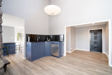 Contemporary kitchen with navy cabinets and black granite countertops, featuring a decorative black door.