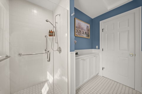 Bright bathroom featuring a walk-in shower and stylish blue walls with storage cabinets.