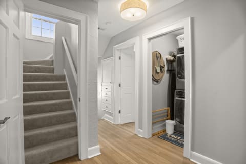 A bright and modern upstairs hallway featuring natural light, a staircase, built-in drawers, and a laundry nook.