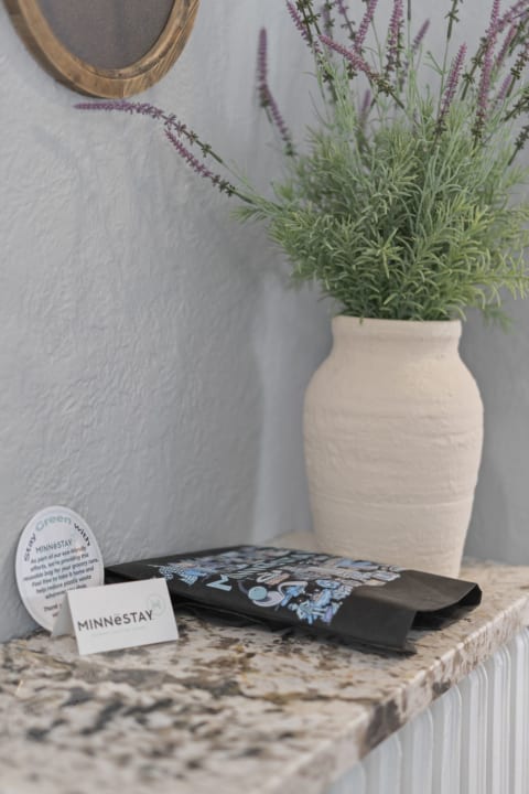 A cozy entryway with a rustic vase of lavender, a decorative bag, and an eco-friendly card, arranged on a granite counter.
