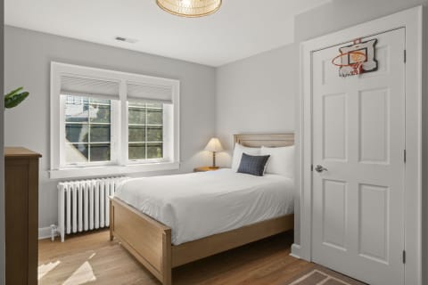 Cozy bedroom with a bed and a mini basketball hoop above the door, filled with natural light.