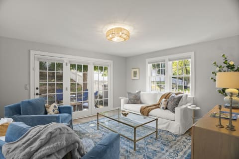A bright living room with turquoise chairs, white sofa, and French doors opening to an outdoor space.